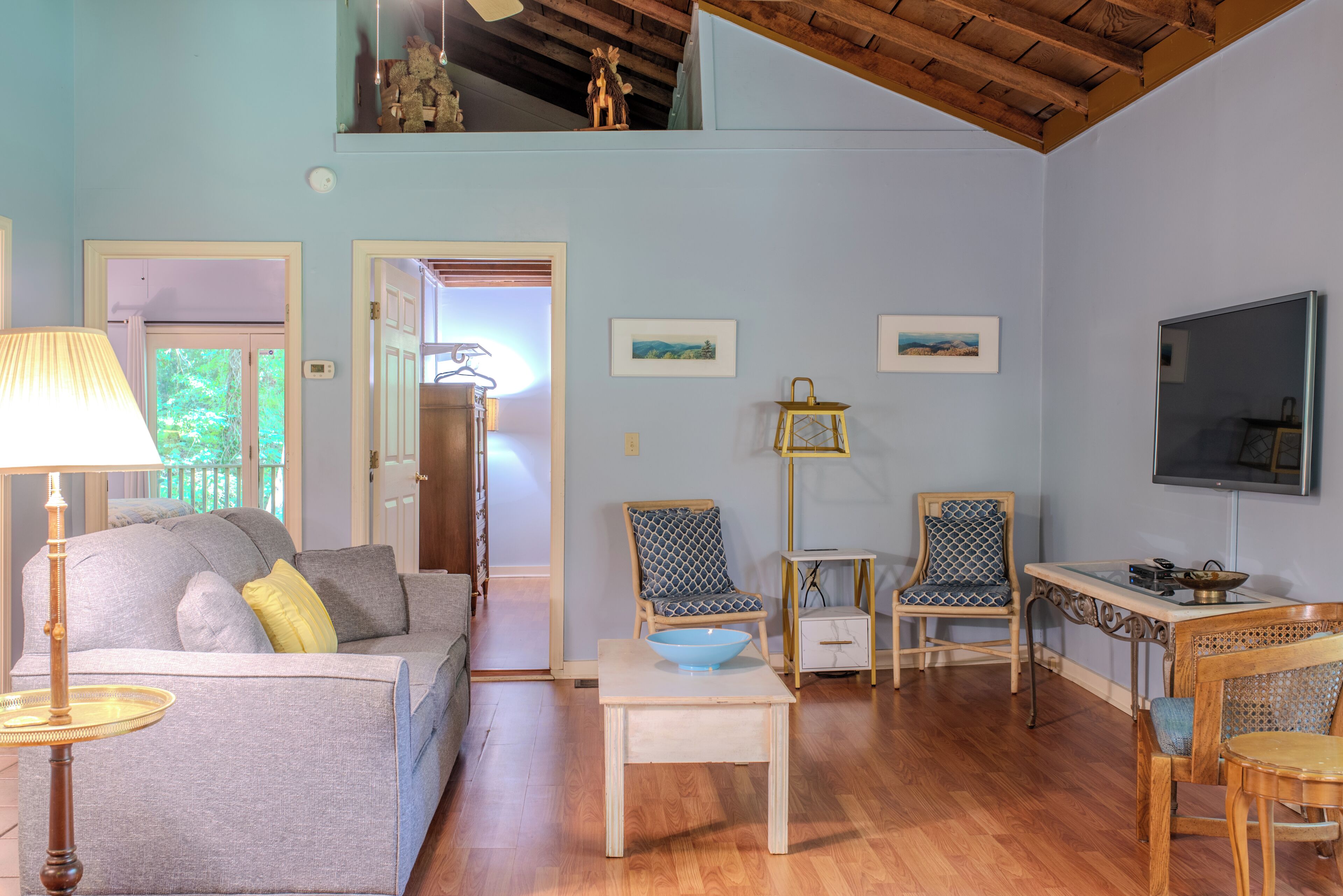 Una sala de estar con sofá, sillas, mesa, lámpara y televisor.