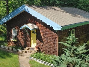 A small brick building with a yellow door and a blue roof.