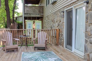 A wooden deck with two Adirondack chairs, a small table, and a patterned rug. - McKinley Edwards Inn (Bryson City)