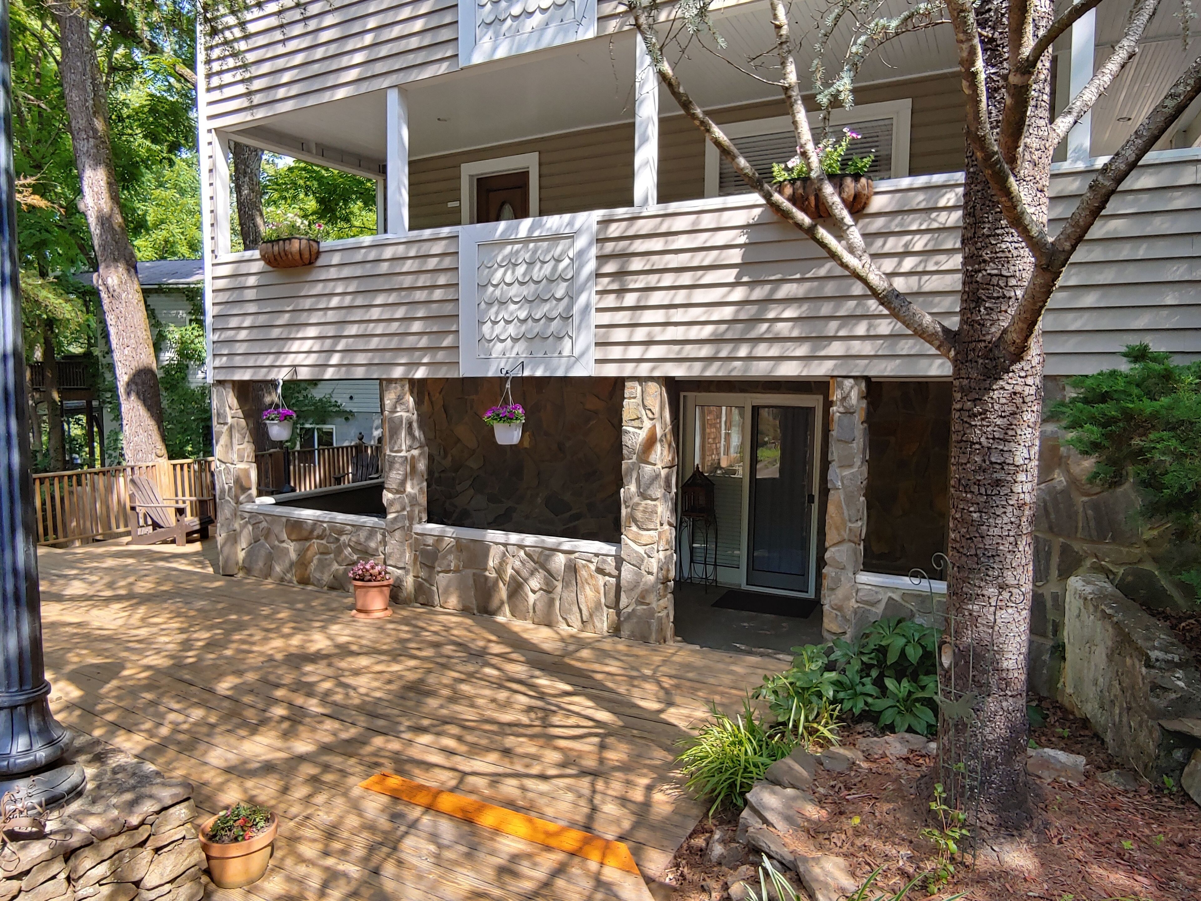 A two-story building with a stone facade, a wooden deck, and outdoor seating.