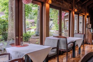 A restaurant with tables and chairs, large windows, and a view of the outdoors. - McKinley Edwards Inn (Bryson City)