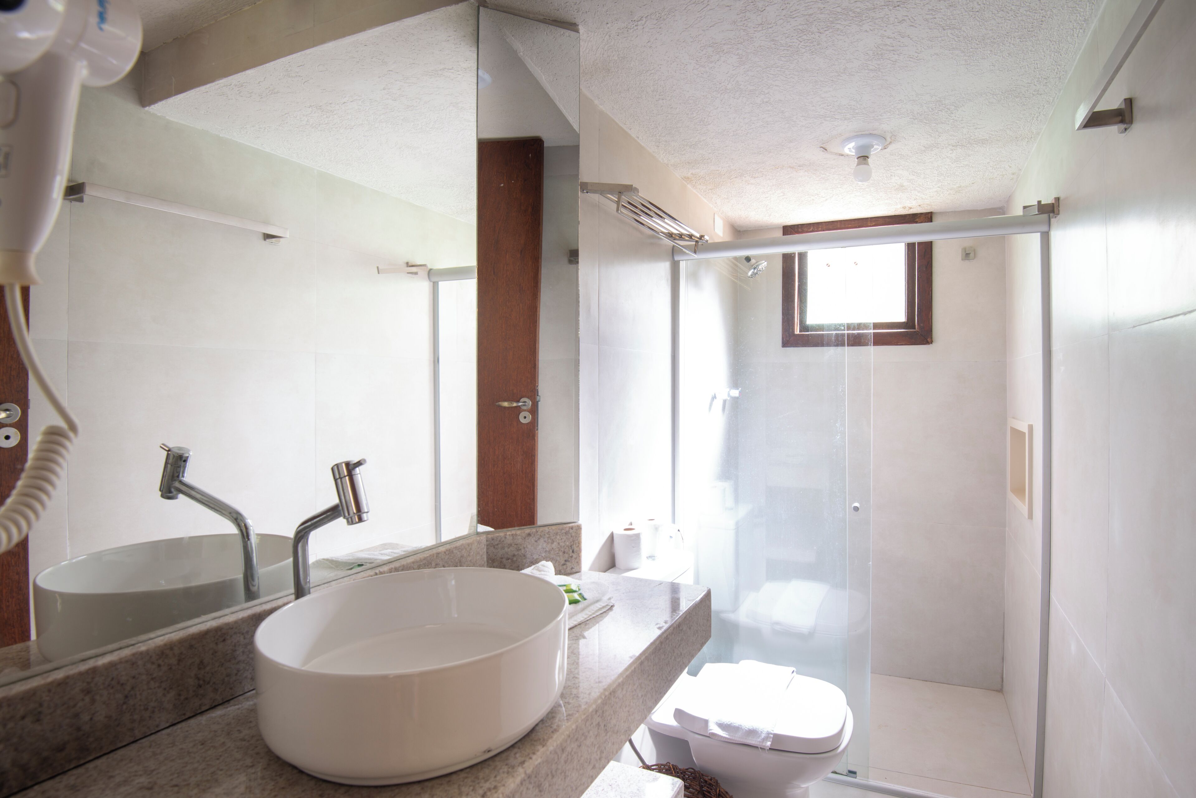 A bathroom with a large oval sink, a mirror, a shower enclosure, and a toilet.