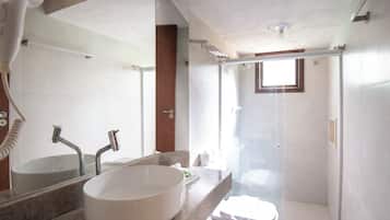 A bathroom with a large oval sink, a mirror, a shower enclosure, and a toilet.