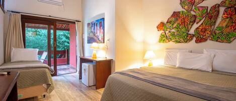 A hotel room with two beds, a desk, a refrigerator, and a painting on the wall.