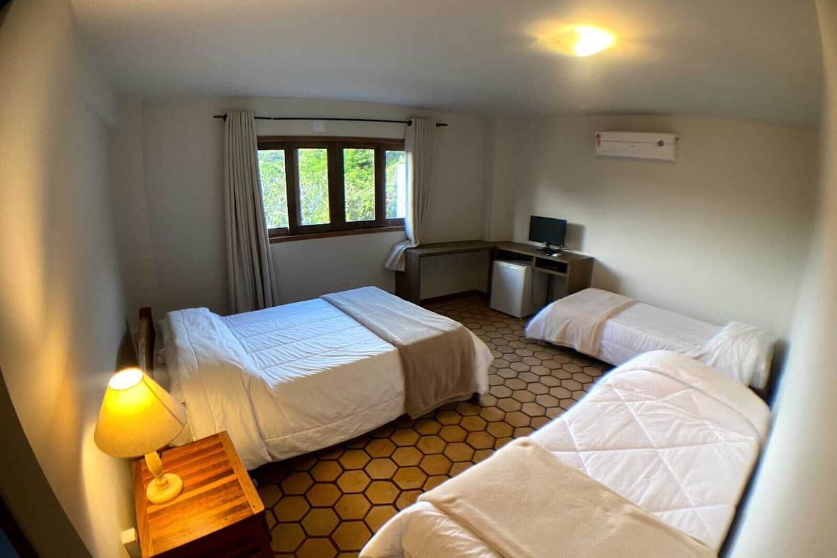 A hotel room with two beds, a desk with a computer, and a window with curtains.