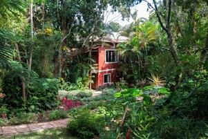 A red building surrounded by dense tropical vegetation.