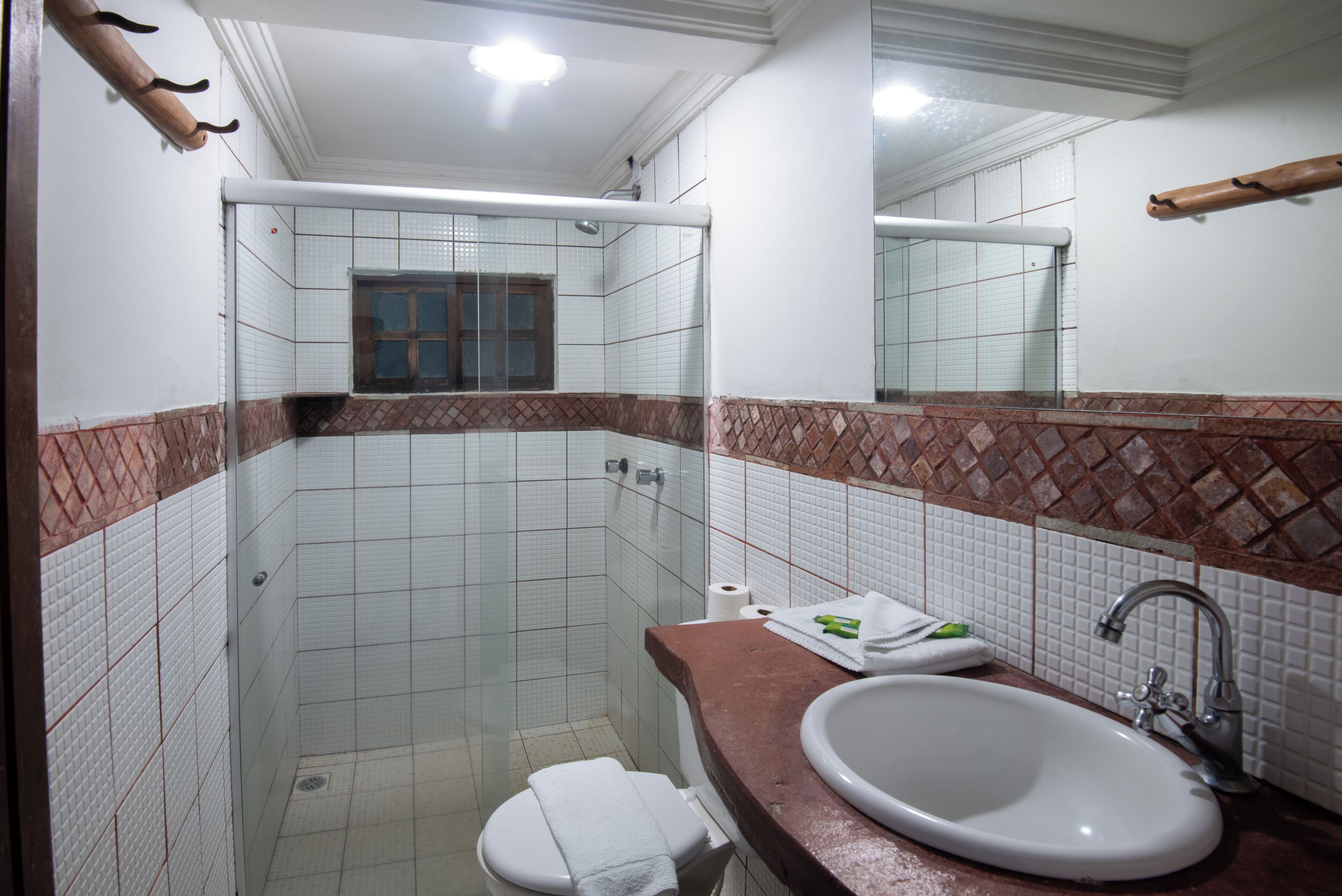 Un baño con lavamanos blanco, espejo y zona de ducha.