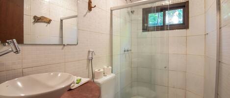 A bathroom with a white sink, a mirror, a shower enclosure, and a toilet.
