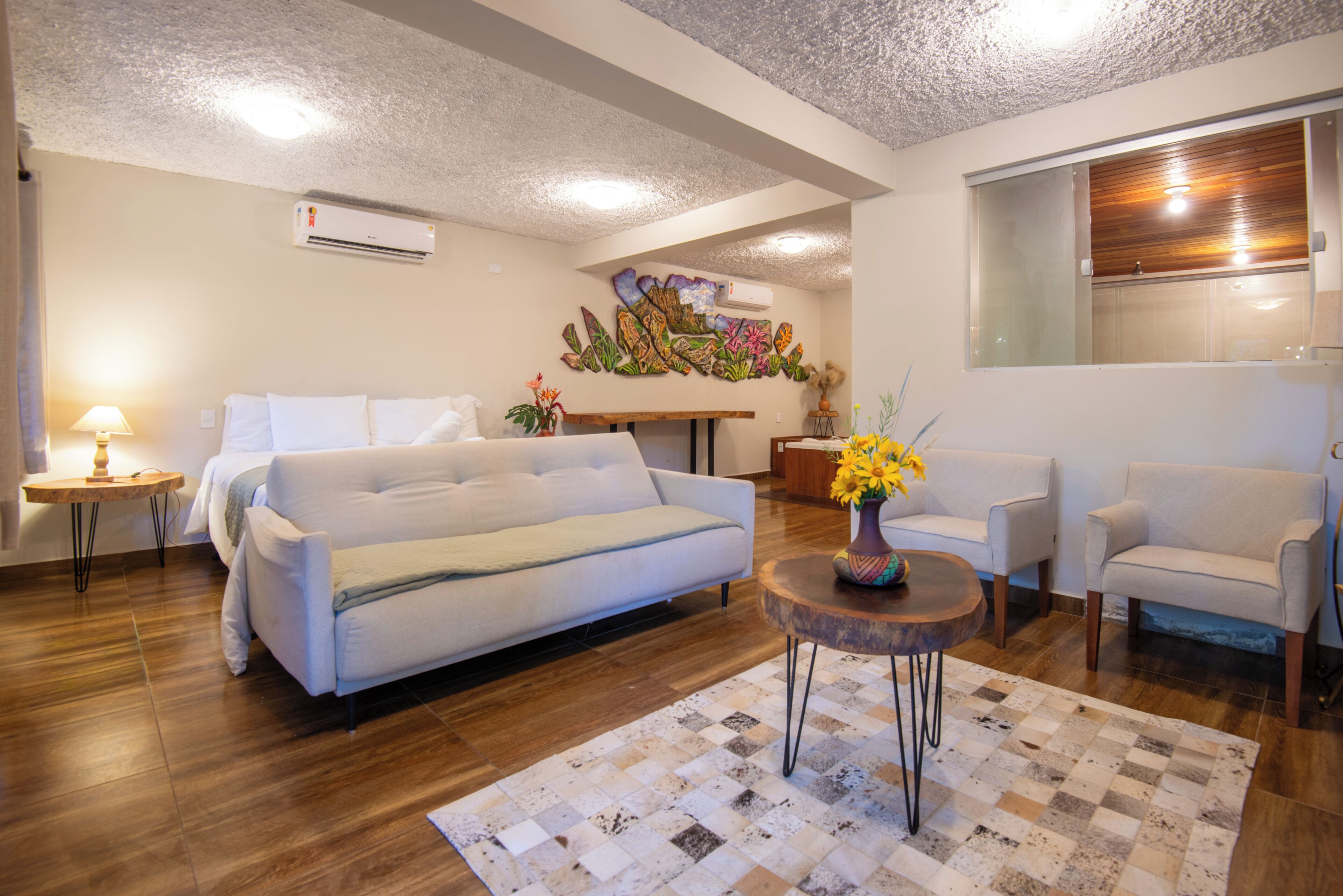 A modern living room with a sofa, armchairs, a coffee table, and a decorative wall piece.