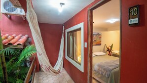 A hotel room with a bed, a window, a door, and a wall-mounted air conditioning unit. - Pousada Lendas do Capão (Palmeiras)