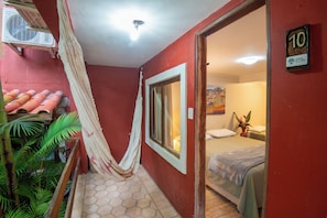 A hotel room with a bed, a window, a door, and a wall-mounted air conditioning unit. - Pousada Lendas do Capão (Palmeiras)