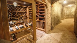 A wine cellar with wooden racks and a stone wall. - Pousada Lendas do Capão (Palmeiras)