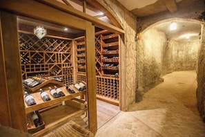 A wine cellar with wooden racks and a stone wall. - Pousada Lendas do Capão (Palmeiras)