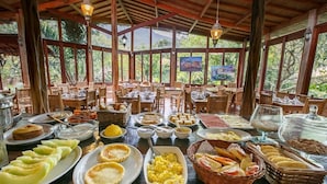 A dining area with multiple tables set for breakfast, featuring a variety of dishes and bread. - Pousada Lendas do Capão (Palmeiras)
