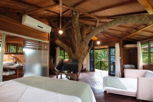 Un dormitorio en una casa del árbol con cama, televisor y baño.