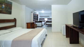 A hotel room with a bed, a desk with a television, a chair, and a window.