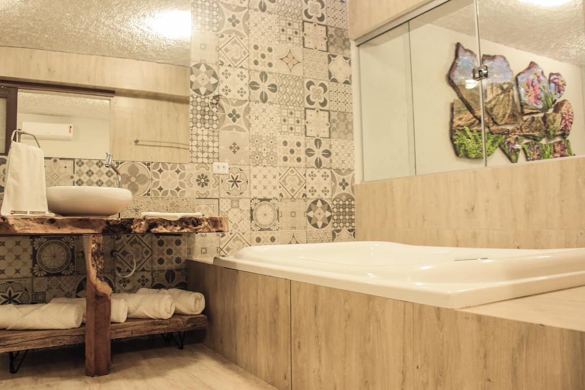 A bathroom with a wooden vanity, a large bathtub, and a mirror.