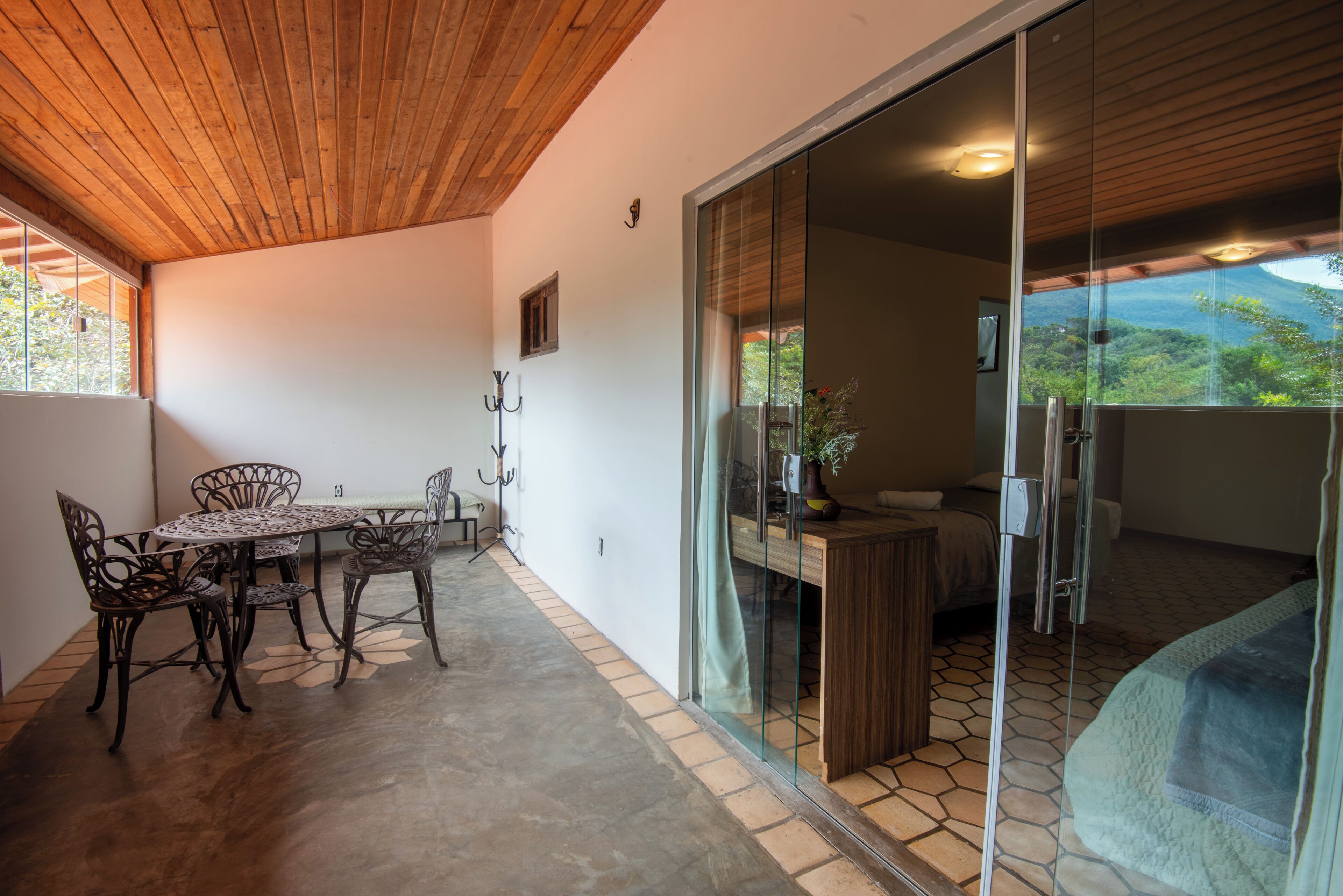 A room with a dining table and chairs, a small window, and a view of a mountainous landscape through a glass door.