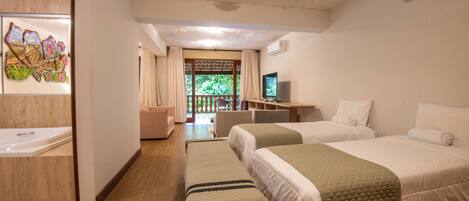 A hotel room with two beds, a desk with a computer, a TV, and a bathroom with a shower and a bathtub.