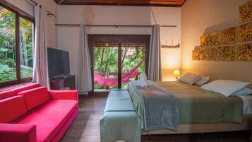 Un dormitorio con una cama, un sofá rojo, un televisor y una hamaca.