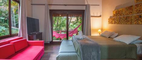 A bedroom with a bed, a red sofa, a television, and a hammock.