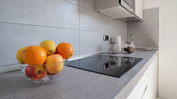 Una cocina con un bol de frutas en la encimera, un microondas y una cafetera.