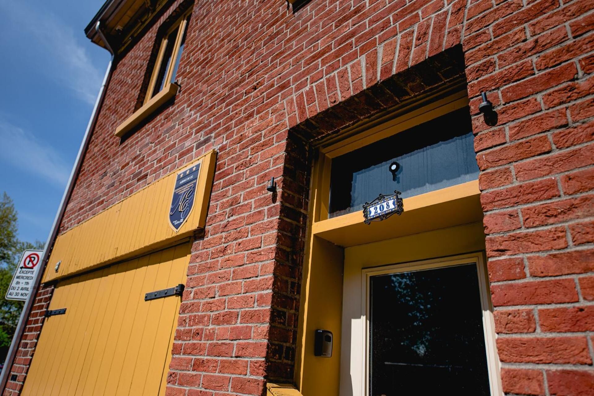 A brick building with a yellow door and a black and white sign above it.