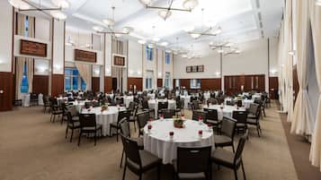 Un amplio salón de banquetes con mesas redondas, sillas y candelabros.