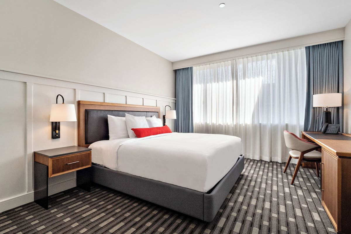 Une chambre d’hôtel avec un grand lit, un bureau et une chaise.