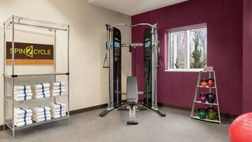 A gym with a spin cycle machine, kettlebells, and a red exercise ball.