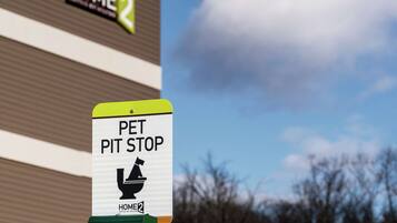 A sign for a pet pit stop with a Home Depot store in the background.