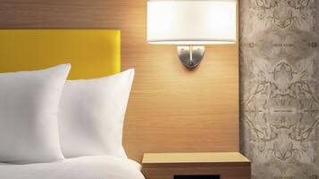 A hotel room with a wooden headboard, a bedside table with a lamp, and a patterned wallpaper.