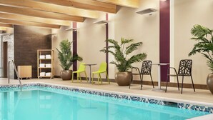 Zona de piscina con techo de madera, asientos y plantas en macetas.