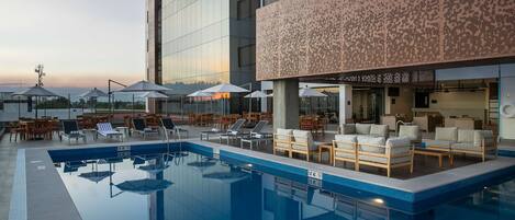 Una piscina al aire libre, sillones reclinables de piscina