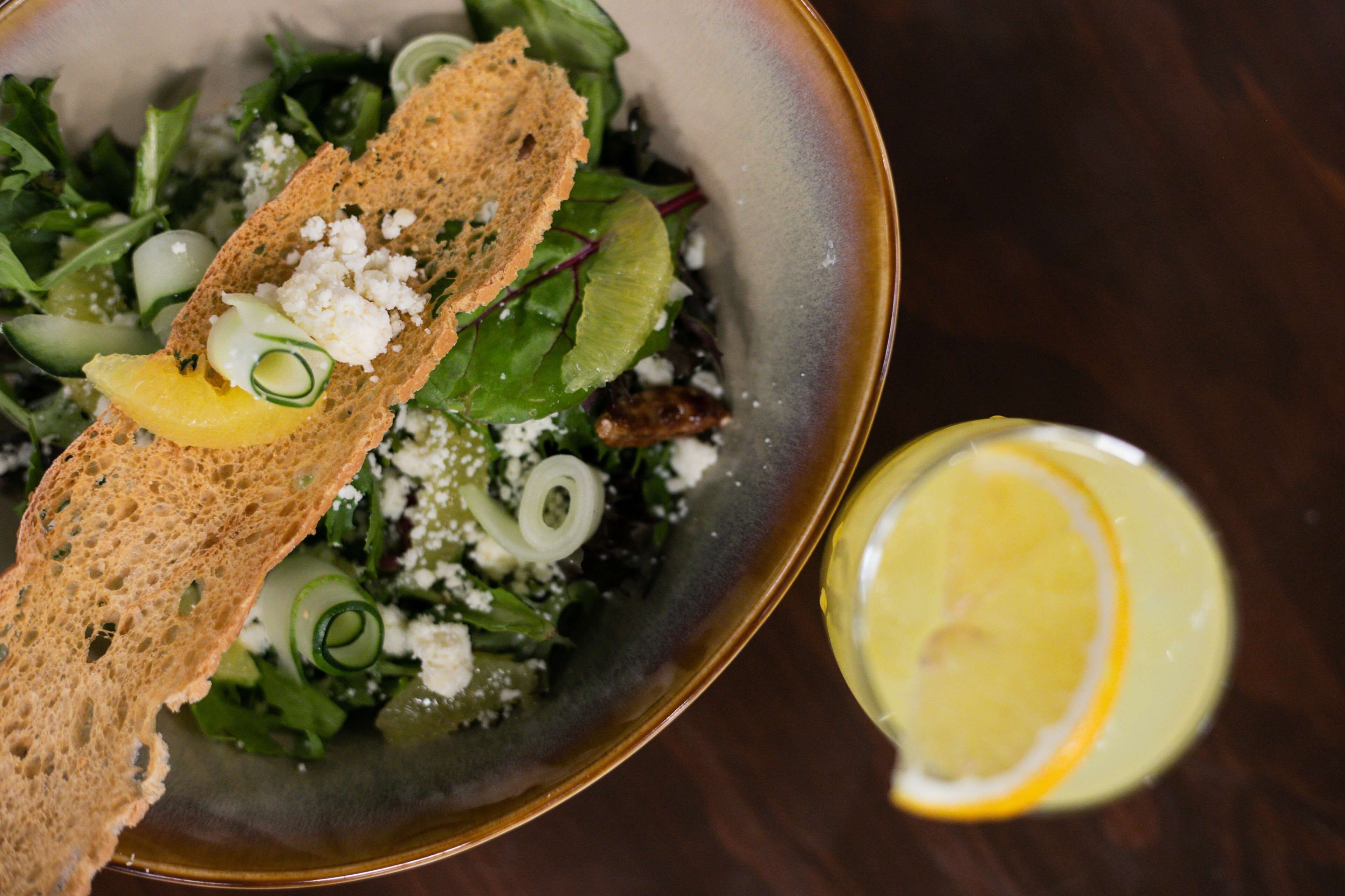 Uma salada com croutons, queijo e fatias de limão.