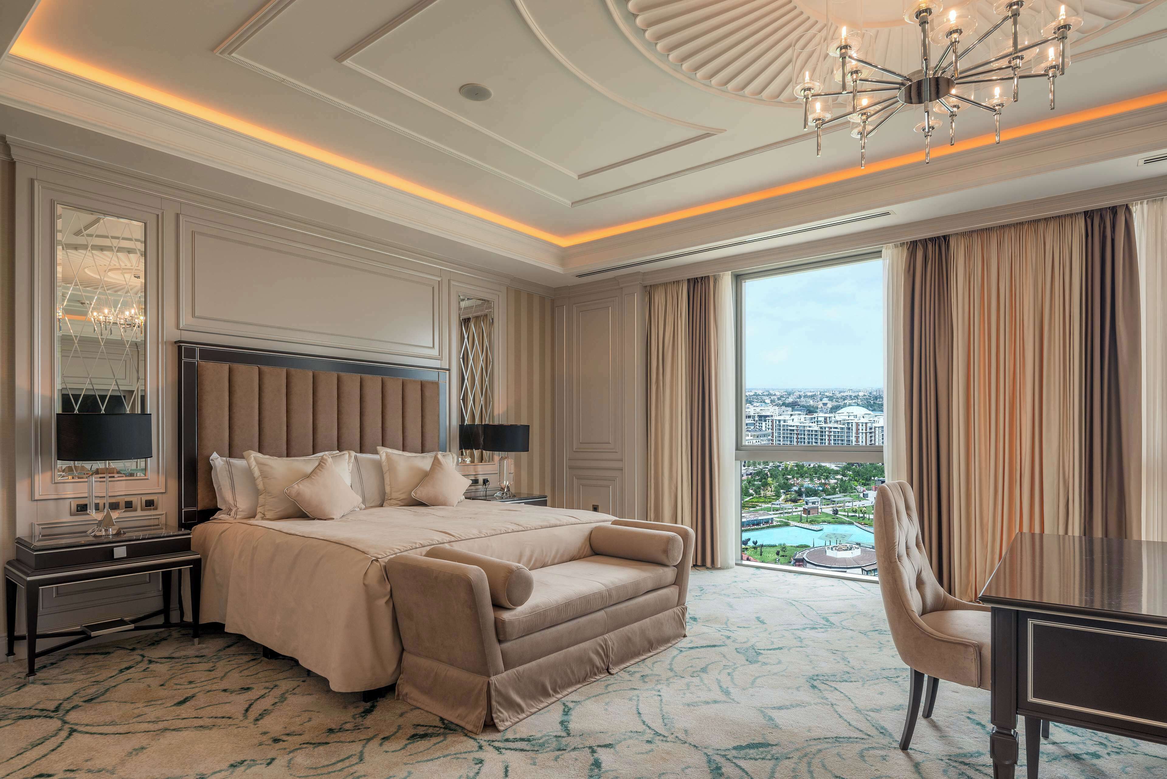 A spacious hotel room with a large bed, a desk, and a view of a cityscape.
