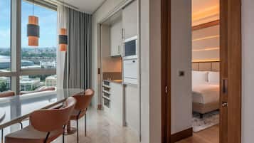 Moderni hotellihuone, jossa on ruokailutila, pieni keittiö ja sänky.