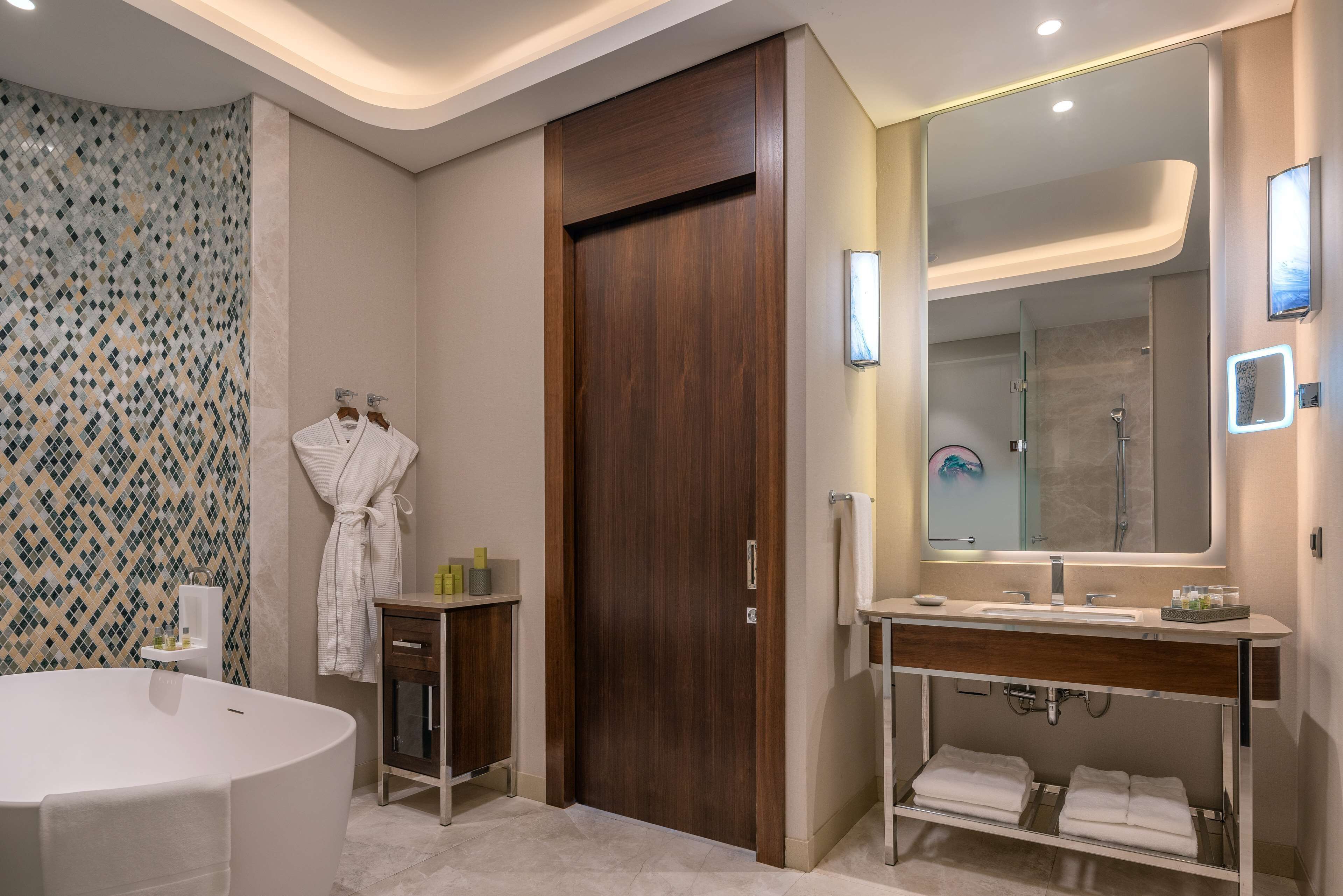 A modern bathroom with a freestanding bathtub, a vanity with a mirror, and a shower area.