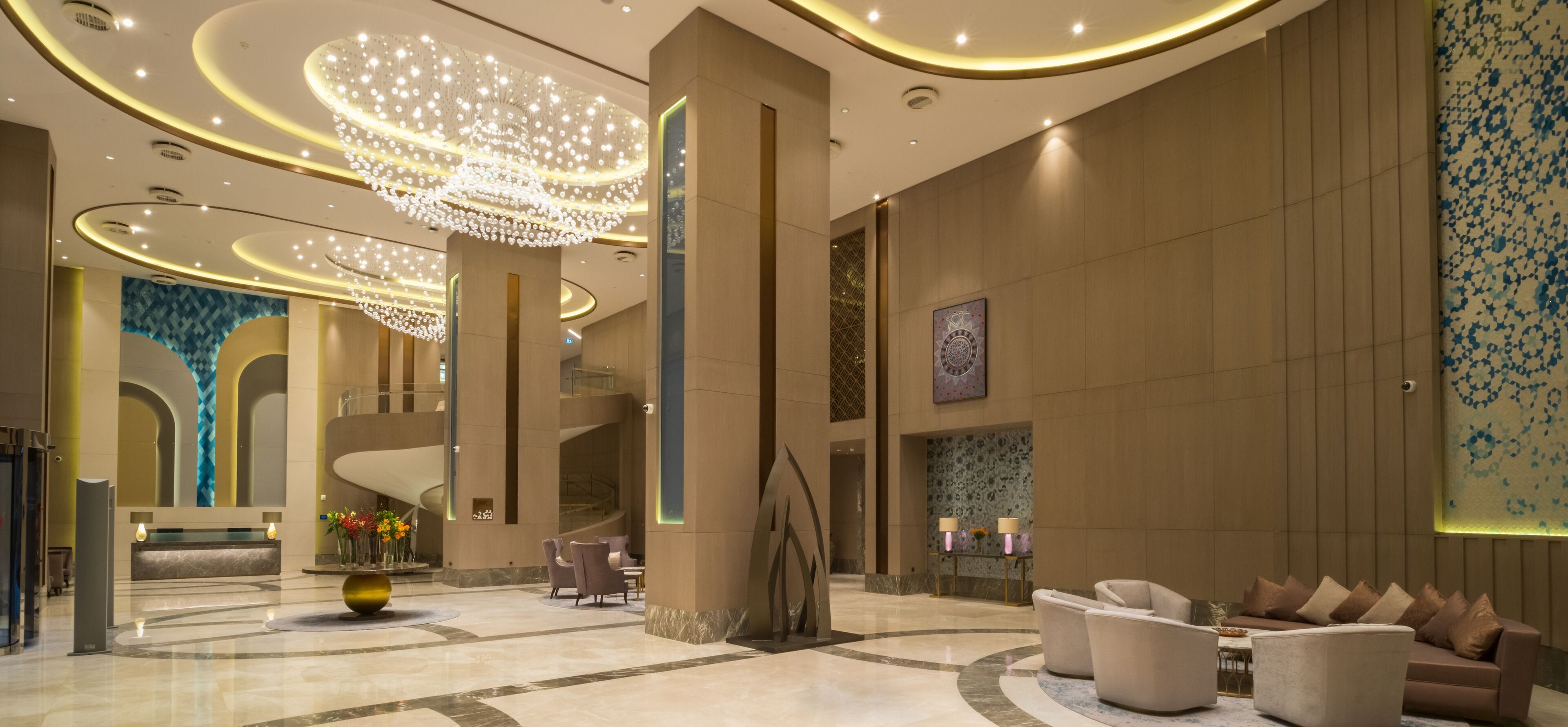 A spacious lobby with a grand chandelier, marble flooring, and modern seating areas.