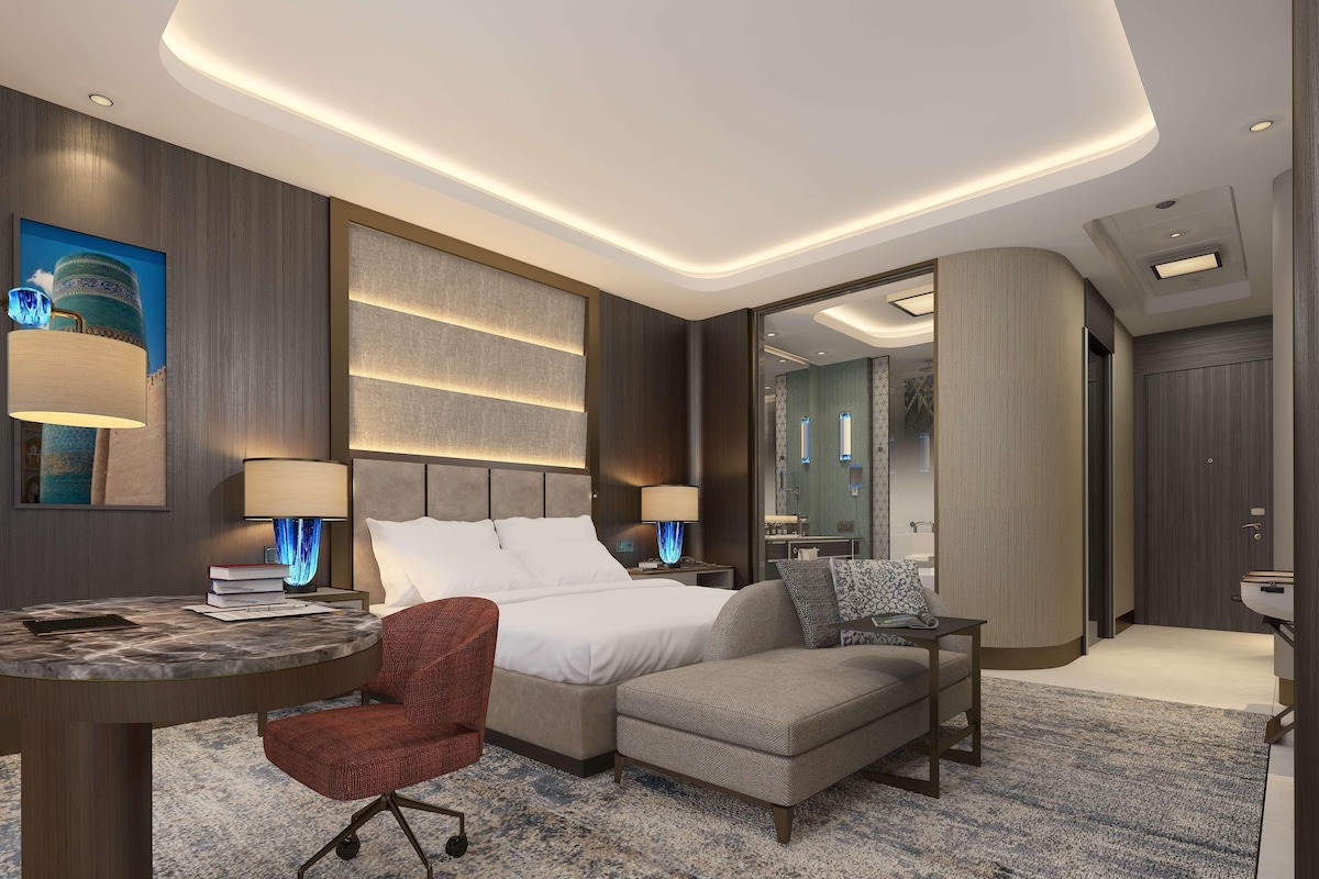 Una habitación de hotel moderna con una cama, un escritorio, una silla y un sofá.