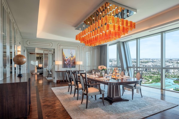 A modern dining area with a large table, chairs, and a unique orange chandelier.