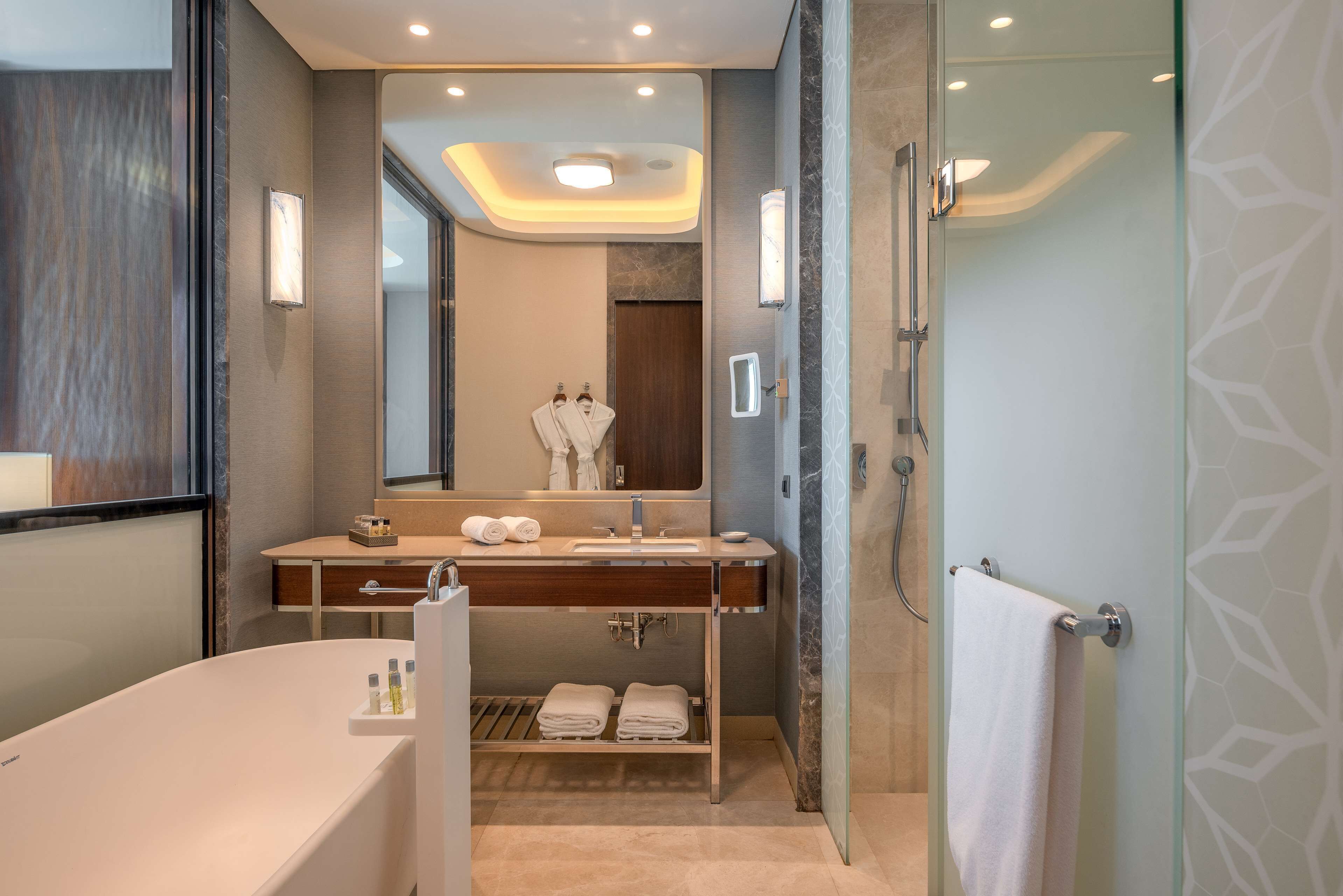 A modern bathroom with a freestanding bathtub, a vanity with a mirror, and a shower area.