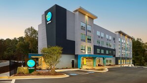 A modern hotel building with a prominent 'tru by Hilton' sign, multiple floors, and a parking lot. - Tru by Hilton Atlanta Northlake Parkway, GA (Atlanta)