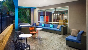 An outdoor patio area with a seating arrangement including a sofa, chairs, and a table. - Tru by Hilton Atlanta Northlake Parkway, GA (Atlanta)