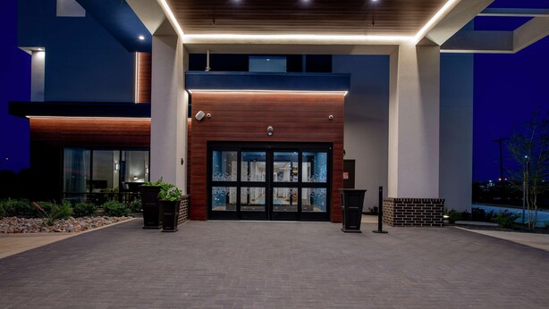 A modern building entrance with a glass door, a brick wall, and a wooden facade. - Hampton Inn & Suites Duncanville Dallas (Duncanville)