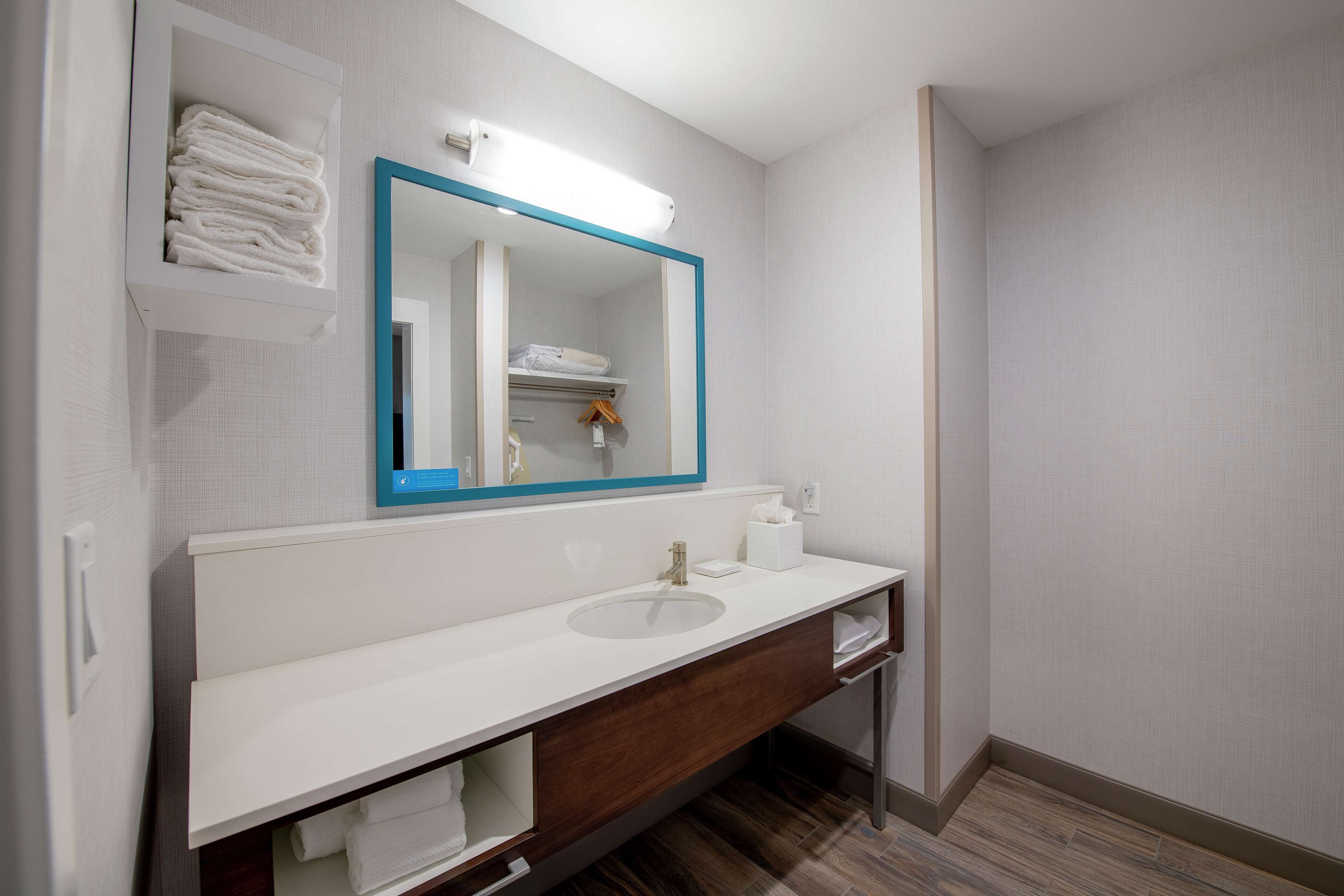 A modern bathroom with a white sink, a mirror with a blue frame, and a towel rack.