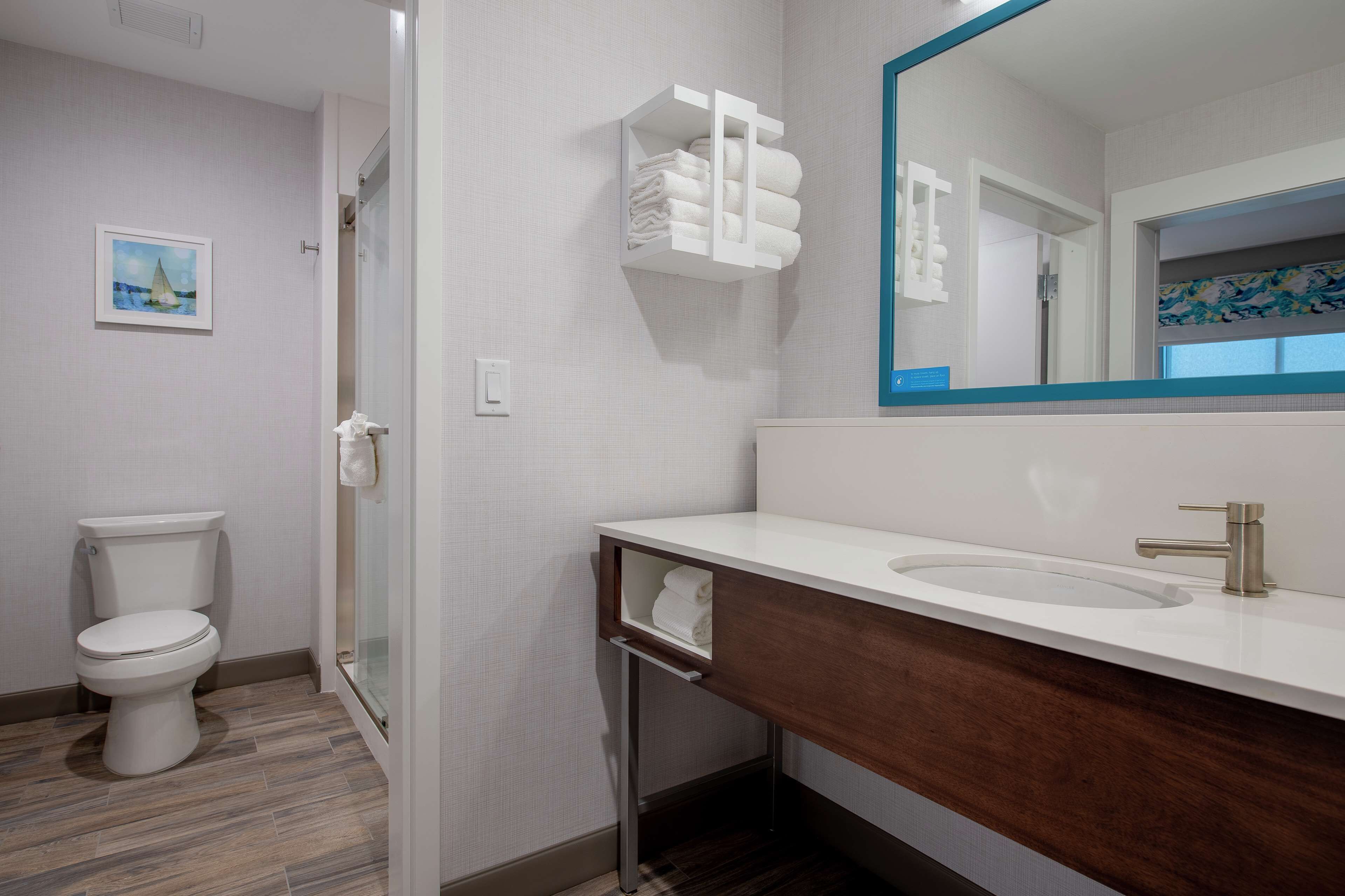 A modern bathroom with a toilet, sink, and mirror.