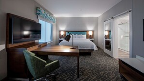 A hotel room with a bed, a desk with a chair, a television, and a sliding door leading to a bathroom. - Hampton Inn & Suites Duncanville Dallas (Duncanville)