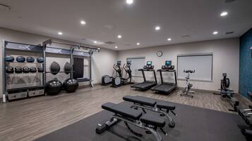 Een moderne sportschool met cardio-apparatuur, krachtstations en diverse fitnessballen.