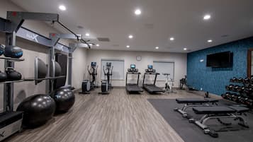 A gym with exercise equipment, treadmills, and a wall-mounted TV.